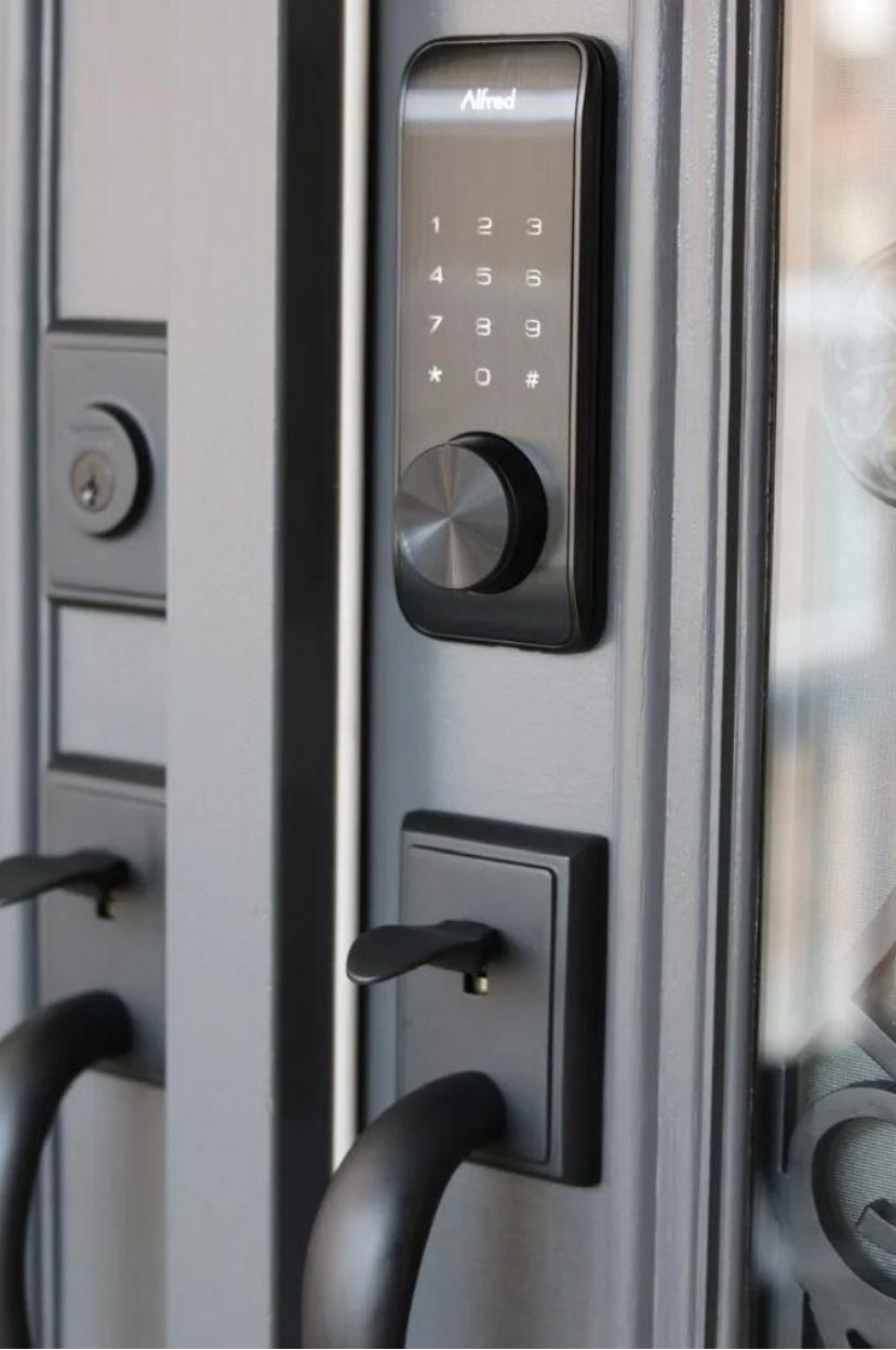Alfred keypad smart lock installed above a matching handleset on an exterior door