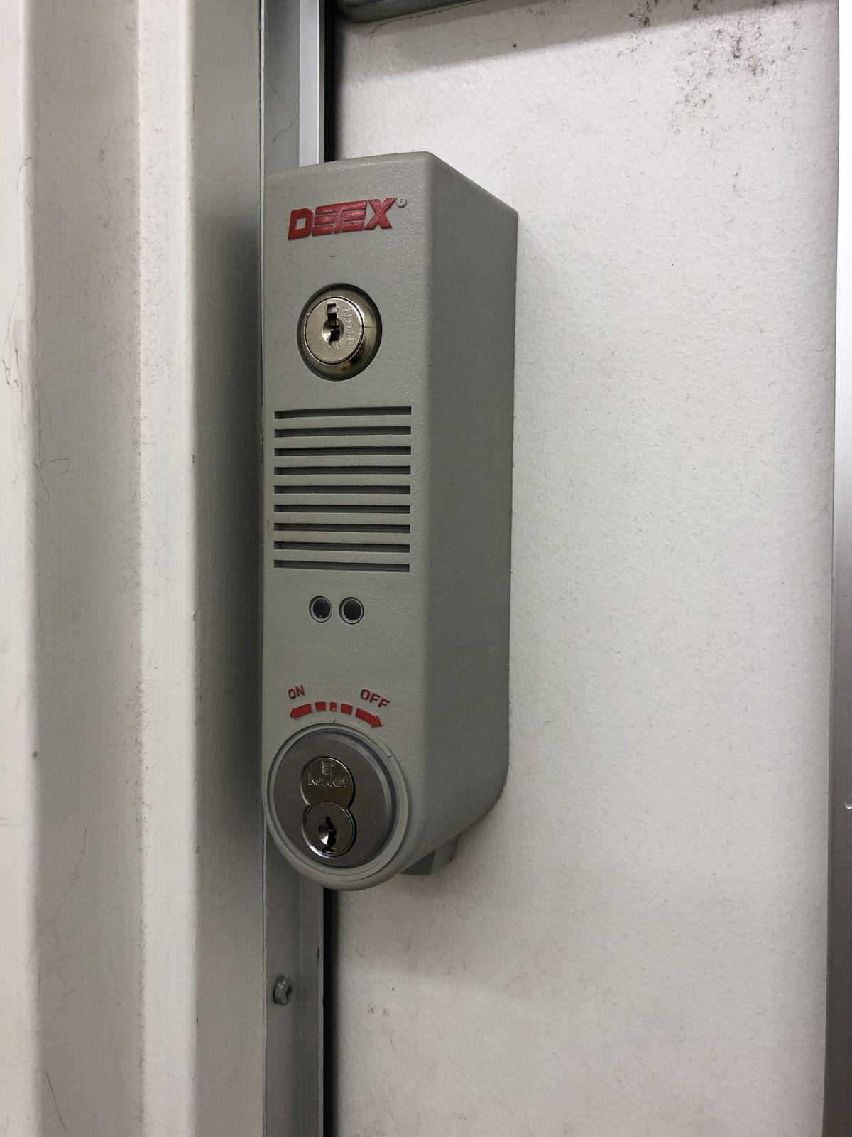 Detex commercial exit alarm and Medeco cylinder on a door frame