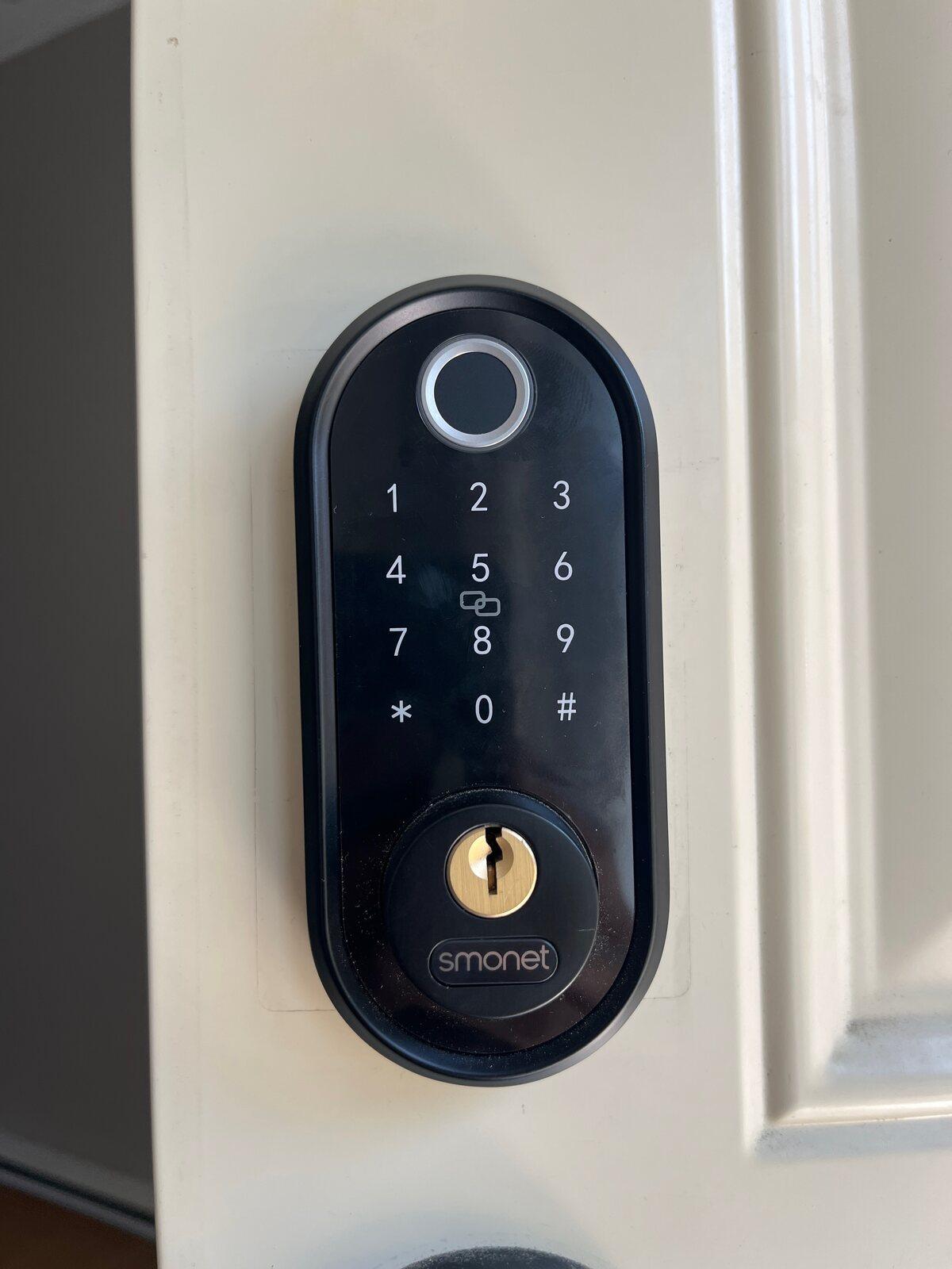 Black Smonet keypad deadbolt installed on a white residential entry door